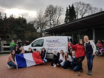 Schüler vor dem France Mobil Auto mit einer Frankreich Flagge  